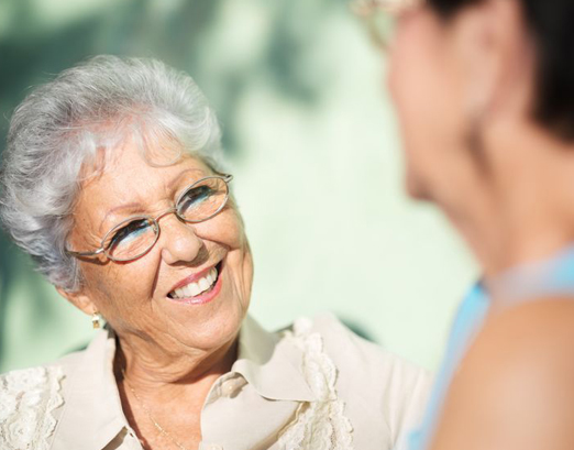 Happy older woman looking at her friend who is out of focus.